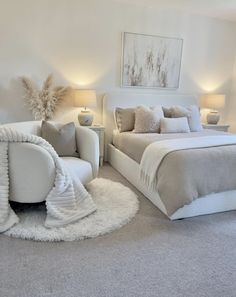 a large white bed sitting in a bedroom next to a chair and table with two lamps on top of it