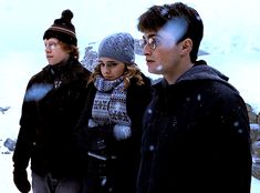 three people standing in the snow looking at something