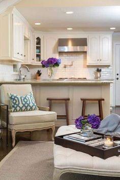 a living room filled with furniture next to a kitchen and dining room table covered in purple flowers