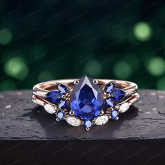 an image of a ring with blue and white stones on the front, sitting on top of a piece of wood