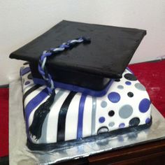 a graduation cap on top of a cake with blue and white stripes, polka dots