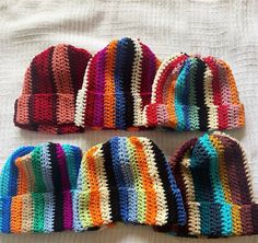 three crocheted hats laying on top of a bed