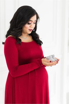 a pregnant woman in a red dress holding a small object