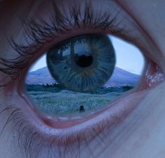 an eye looking into the distance with mountains in the background