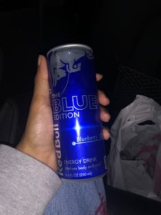 a person holding a blueberry energy drink in their left hand, with the light on