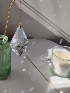 a green glass vase with a candle on it next to a clear glass cup filled with water