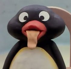 a close up of a toy penguin with its tongue sticking out and eyes wide open