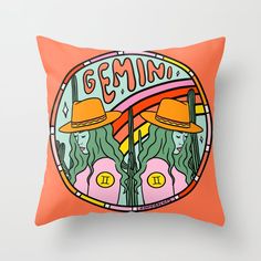 an orange pillow with the words gemin on it and two women wearing yellow hats