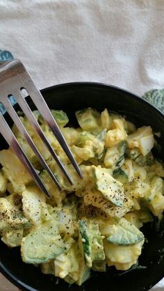 a fork in a black bowl filled with pasta and broccoli florets