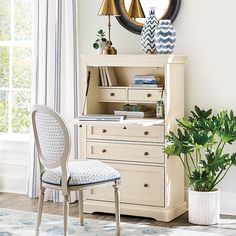 a white desk with a chair, mirror and potted plant in front of it