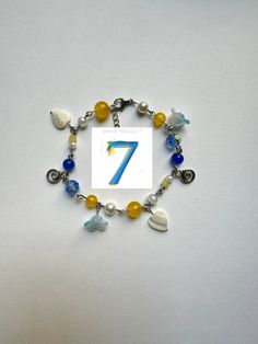 a bracelet with beads, charms and a number 7 on it's front end