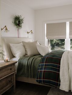 a bedroom with white walls and plaid bedding on the bed is decorated with greenery