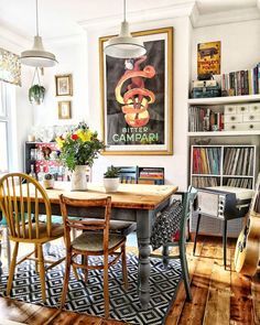 a dining room table and chairs in front of a book shelf with books on it