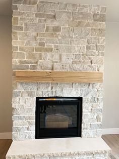 a stone fireplace with a wood mantel in the middle and white brick on top