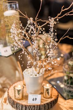 a white vase filled with lots of flowers on top of a wooden table next to candles