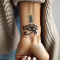 a woman's wrist with an egyptian eye tattoo on her left arm and the word,