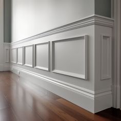 an empty room with white paneling and wood floors