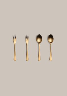 gold spoons and forks lined up against a gray background