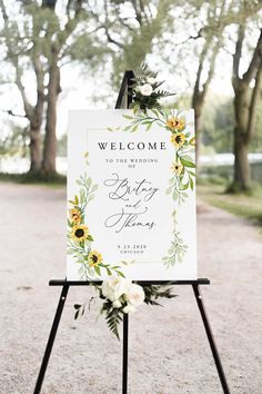 a welcome sign with sunflowers and greenery is displayed on an easel