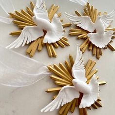 three white and gold bird brooches with ribbons on the bottom one is flying