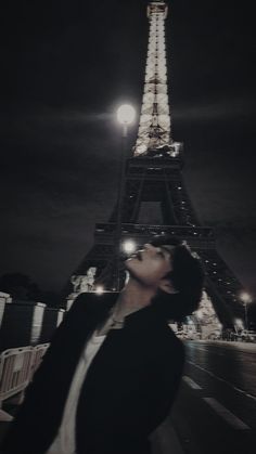 a woman standing in front of the eiffel tower at night with her eyes closed