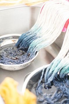 two buckets filled with blue and white dye sitting on top of a metal table