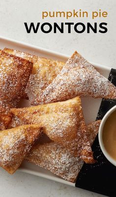 pumpkin pie wontons on a white plate with dipping sauce in the middle and powdered sugar sprinkled on top