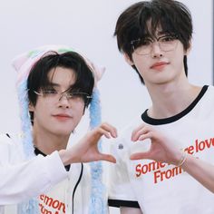 two young men standing next to each other with their hands in the shape of a heart