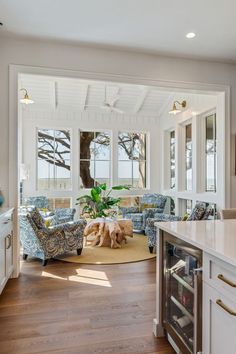 a living room filled with furniture next to a kitchen and an open door leading to the outside