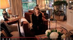 a woman sitting in a living room next to a table with flowers on top of it