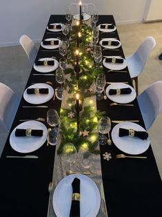 the table is set with black and white plates, silverware, and christmas decorations