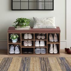 a wooden shoe rack with shoes and plants in front of a mirror on the wall