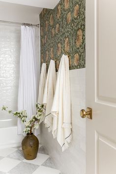 a bathroom with towels hanging on the wall and a potted plant next to it