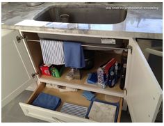 an open cabinet in a kitchen filled with cleaning supplies and other household items next to a sink