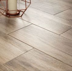 a wooden floor with a vase and candle on it