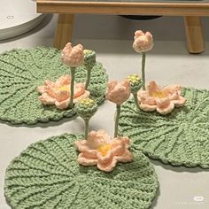 crocheted flowers are placed on top of water lilies in the shape of leaves