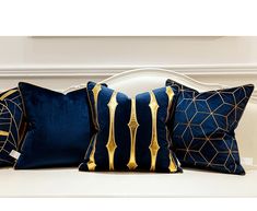 three blue and gold pillows sitting on top of a white bench