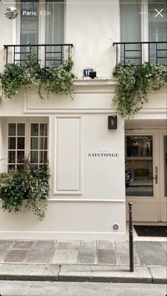 a white building with plants growing on it's windows and balconies above the doors