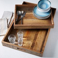 two wooden trays with plates and glasses on them