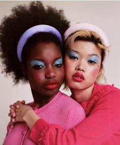 two women hugging each other with bright makeup