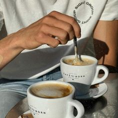 two cups of coffee with spoons in them