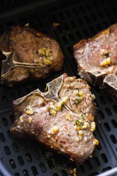 three steaks are cooking on the grill