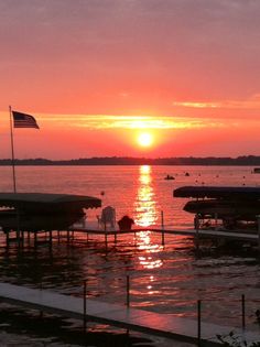 the sun is setting over some boats in the water