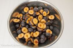 a bowl filled with black olives on top of a white table