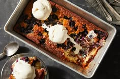 a pan filled with blueberry cobbler and ice cream on top of a table