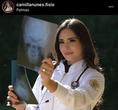 a woman in white coat holding up an x - ray