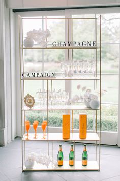 champagne bottles and glasses on a shelf in front of a window