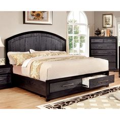 a bedroom with a bed, night stand and dressers in the middle of it