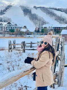 a woman standing next to a fence in the snow