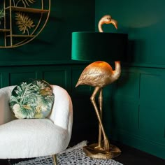 a gold flamingo lamp sitting next to a white chair in a green living room